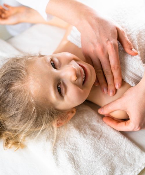 a woman gives a massage to a little girl, children's massage, prevention of scoliosis, osteopathy.